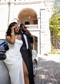 a man and woman standing next to a car