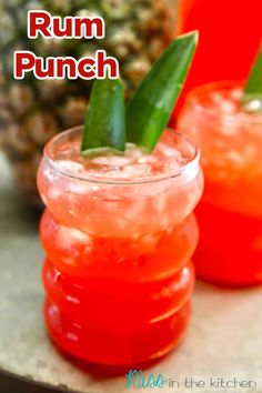 three cocktails with pineapple garnish sit on a tray next to a pineapple