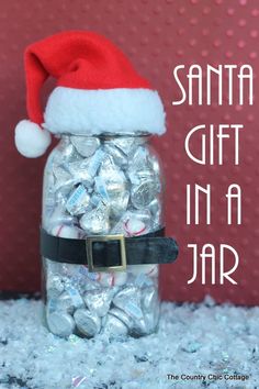 a santa hat sitting on top of a glass jar filled with silver and white candies