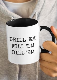 a person holding a coffee mug with the words drill em bill'em on it