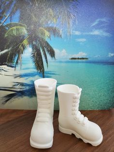 a pair of white boots sitting on top of a wooden table next to a palm tree