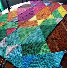 a multicolored knitted rug sitting on top of a wooden table