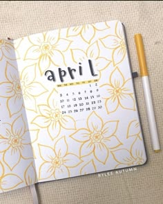 an open notebook with the word april written on it next to a pen and pencil