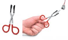 a pair of red scissors being held by a hand with two black handles and one white handle