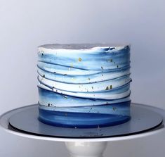 a blue and white cake with gold sprinkles on it sitting on a plate