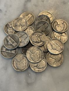 a pile of silver coins sitting on top of a marble counter next to each other