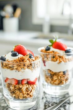 two cups filled with granola and strawberries