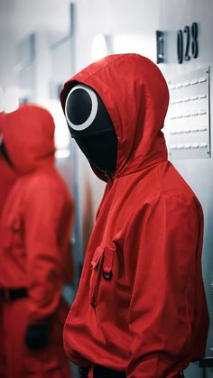 a person in a red hooded jacket is looking into a mirror