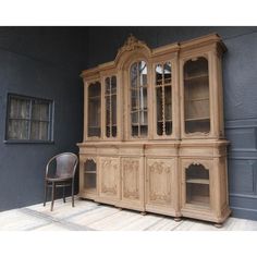 an old wooden china cabinet next to a chair