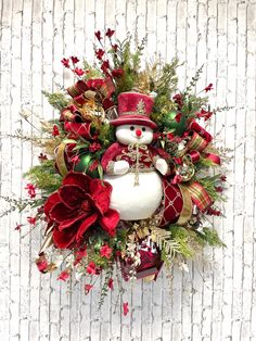 a christmas wreath with a snowman and poinsettis on it against a white wall