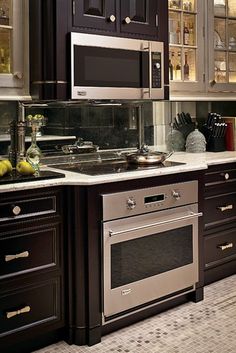 a kitchen with black cabinets and stainless steel appliances, including a microwave above the stove