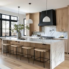 a large kitchen with marble counter tops and stools in front of the center island