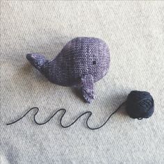 two balls of yarn sitting on top of a bed next to a knitted whale