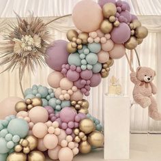 a bunch of balloons that are in the air with a teddy bear next to them