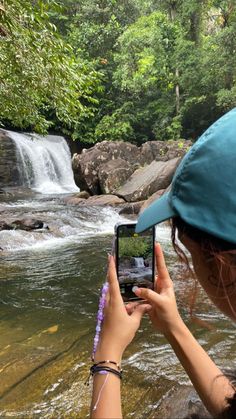 a woman taking a photo of a waterfall