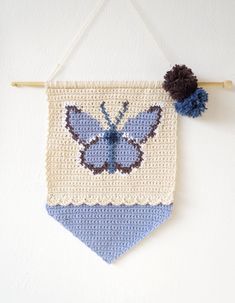 a crocheted blue and white banner hanging on a wall with a pom - pom