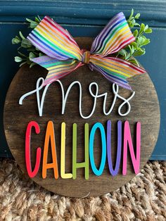 a wooden sign with the word mom's cahoun painted on it and a bow