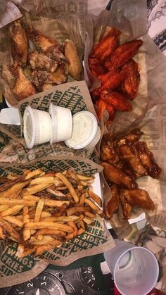 there are many different foods on the table and one is chicken wings, fries, coleslaw