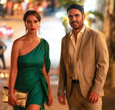 a man and woman dressed in formal wear standing next to each other on the street