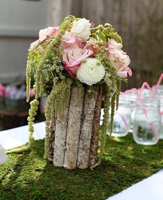 a vase filled with flowers sitting on top of a moss covered table