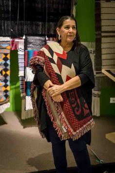 a woman is standing in front of some quilts