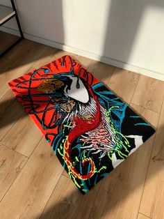 a colorful rug on the floor next to a table and chair in a room with hard wood floors