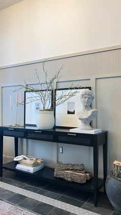 two vases with flowers on top of a black table in front of a mirror