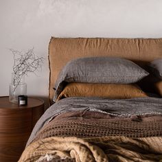 a bed that has some pillows on top of it and a vase with flowers next to it