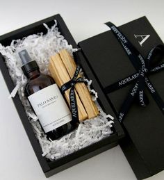 an open black box containing two bottles of wine and bamboo sticks with a ribbon around it