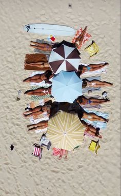 a group of people standing on top of a sandy beach next to an open umbrella