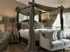 a bedroom with four poster bed and green drapes