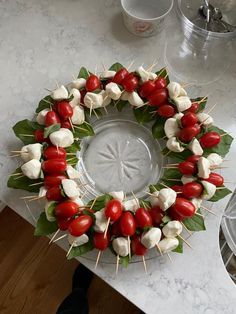 a wreath made out of tomatoes and marshmallows on a marble counter top