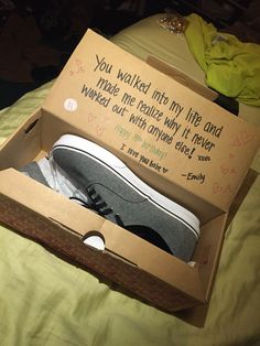 an open shoe box sitting on top of a bed with someone's handwritten note