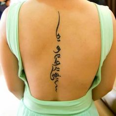 the back of a woman's upper body with arabic writing on her lower back