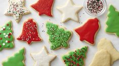 christmas cookies decorated with icing and sprinkles are arranged on a white surface