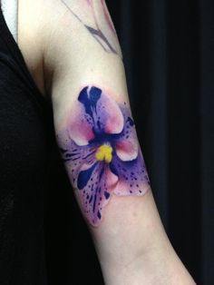 a woman's arm with a purple flower tattoo on the left side of her arm