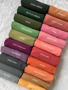 many colors of t - shirts are lined up on a white blanket with the names of each