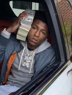 a man sitting in the back seat of a car while holding money up to his face