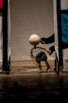 a person with a baseball bat standing next to a stuffed animal wearing a hat and holding a bag