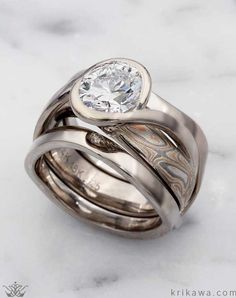 a couple of rings sitting on top of a white marble surface with a diamond in the center