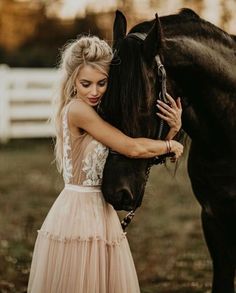 a beautiful blonde woman standing next to a black horse