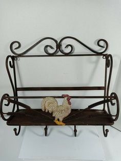 a rooster figurine sitting on top of a metal shelf next to a white wall