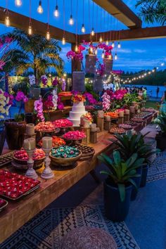 a table filled with lots of desserts and flowers on it's sides at night