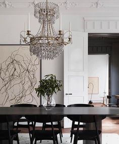 a chandelier hangs from the ceiling above a dining room table with black chairs