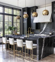 an elegant kitchen with marble counter tops and gold pendant lights hanging from the ceiling over the island