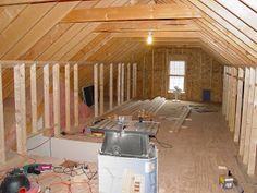 an unfinished attic with wood flooring and exposed rafters on the walls, along with other construction materials