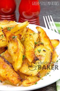 some fried potatoes on a white plate with fork and two red bottles in the background