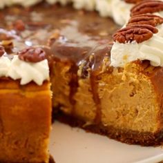 a piece of pumpkin cheesecake with pecans and whipped cream on top is cut from the cake