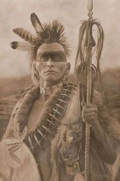 an old photo of a native american man holding a stick and two feathers on his head