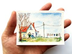 a person holding up a small card with a house on it